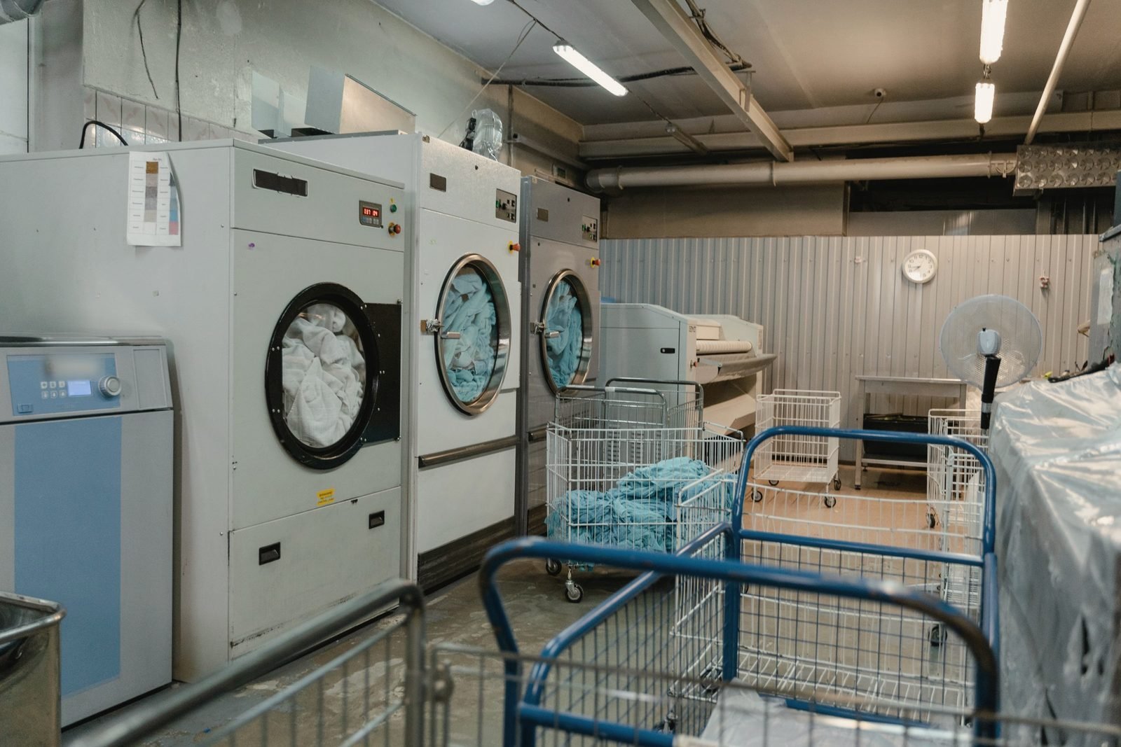 A commercial laundry room with machines and rolling carts