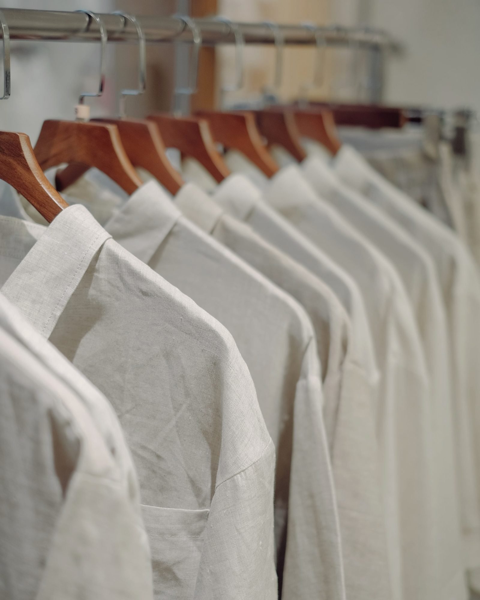 A receding rail of pressed shirts on wooden hangers